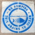 Blue stencil on pavement in La Jolla "No Dumping. This Drains to Ocean."